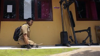 Seorang guru CPNS, Mohamat Hikmat (26), menaiki papan luncur di Sekolah Luar Biasa (SLB) Kabupaten Batang, Jawa Tengah, Senin (25/11). [ANTARA FOTO/Harviyan Perdana Putra]