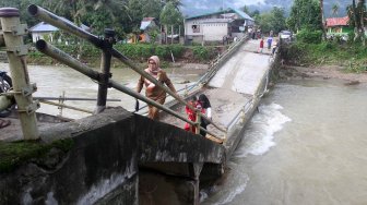 Sejumlah warga melintasi jembatan yang ambruk di Desa Sungai Pangkua, Kecamatan Koto Parik Gadang Diateh, Solok Selatan, Sumatera Barat, Selasa (26/11).[ANTARA FOTO/Muhammad Arif Pribadi]