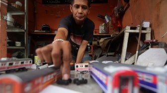 Iskandar (52) menyelesaikan pembuatan miniatur kereta api di kawasan Manggarai, Jakarta, Rabu (27/11).[Suara.com/Angga Budhiyanto]