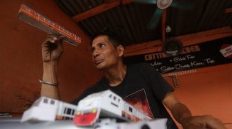 Iskandar (52) menyelesaikan pembuatan miniatur kereta api di kawasan Manggarai, Jakarta, Rabu (27/11).[Suara.com/Angga Budhiyanto]