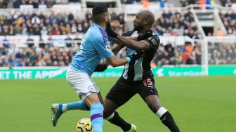 Bek Newcastle United Ciaran Clark bersaing dengan bek Manchester City John Stones saat pertandingan sepak bola Liga Inggris antara Newcastle melawan Manchester City di St James 'Park, Newcastle-upon-Tyne, Inggris, Sabtu (30/11). [Lindsey Parnaby / AFP]