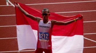 Pelari Indonesia Agus Prayogo mengibarkan bendera Merah Putih seusai memasuki garis finish nomor marathon putra SEA Games 2019 di Stadion Atletik New Clark City, Clark, Filipina, Jumat (6/12). [ANTARA FOTO/Aditya ES Wicaksono]