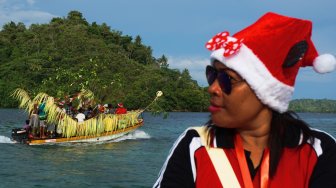 Seorang warga mengikuti prosesi adat perahu hias berkunjung ke setiap rumah, di Distrik Kepulauan Ambai, Kepulauan Yapen, Sabtu (07/12). [ANTARA FOTO/Indrayadi TH]