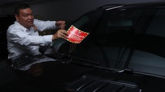 Petugas Samsat Jakarta Pusat menempelkan stiker 'Objek Pajak' pada mobil mewah saat razia supervisi pencegahan pajak mobil mewah di Apartemen Pavilion, Jakarta Pusat, Senin (9/12). [Suara.com/Angga Budhiyanto]