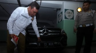 Petugas Samsat Jakarta Pusat menempelkan stiker 'Objek Pajak' pada mobil mewah saat razia supervisi pencegahan pajak mobil mewah di Apartemen Pavilion, Jakarta Pusat, Senin (9/12). [Suara.com/Angga Budhiyanto]