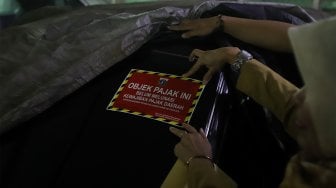 Petugas Samsat Jakarta Pusat menempelkan stiker 'Objek Pajak' pada mobil mewah saat razia supervisi pencegahan pajak mobil mewah di Apartemen Pavilion, Jakarta Pusat, Senin (9/12). [Suara.com/Angga Budhiyanto]