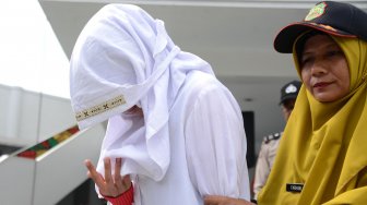 Terpidana pelanggar hukum Syariat Islam (kiri) dikawal petugas seusai menjalani eksekusi cambuk di Taman Sari, Banda Aceh, Selasa (10/12). [ANTARA FOTO/Ampelsa]