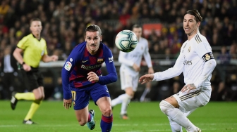 Pemain depan Barcelona Antoine Griezmann (tengah) dan pemain belakang Real Madrid Sergio Ramos memperhatikan bola selama pertandingan sepak bola Liga Spanyol "El Clasico" antara Barcelona melawan Real Madrid di Camp, Barcelona, Spanyol, Kamis (18/12) dini hari WIB. [JOSE JORDAN / AFP]
