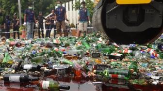 Petugas gunakan alat berat memusnahkan barang bukti minuman keras di Kantor Bea Cukai, Rawamangun, Jakarta, Kamis, (19/12). [Suara.com/Angga Budhiyanto]