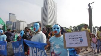 Warga melakukan aksi mengecam tindakan kekerasan pemerintah Cina terhadap muslim Uighur di kawasan Bundaran Hotel Indonesia, Jakarta, Minggu (22/12). [ANTARA FOTO/Reno Esnir]
