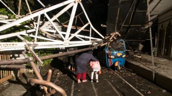 Warga sekitar yang memaksa untuk pulang kerumahnya di seberang jalan yang tertutup tower roboh milk RRI di Jalan Antena VII, Radio Dalam, Jakarta Selatan, Minggu (22/12) malam. [Suara.com/Alfian Winanto]

