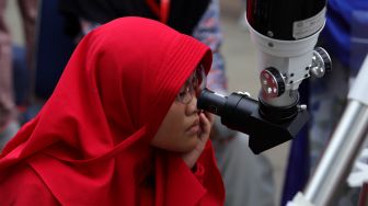 Pengunjung menggunakan kacamata khusus untuk melihat gerhana matahari cincin dari Planetarium Taman Ismail Marzuki, Jakarta, Kamis (26/12). [Suara.com/Angga Budhiyanto]