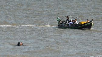 Pengemudi perahu motor mencoba mendekat ke arah korban kecelakaan kapal yang terombang-ambing di perairan Kuala Tungkal, Tanjungjabung Barat, Jambi, Jumat (27/12). [ANTARA FOTO/Wahdi Septiawan]