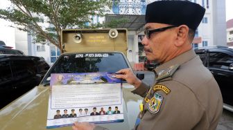 Personel Satpol PP dan Wilayatul Hisbah (Polisi Syariat Islam) memperlihatkan seruan bersama larangan perayaan pergantian tahun masehi dari 2019 ke 2020 di Banda Aceh, Aceh, Jumat (27/12). [ANTARA FOTO/Irwansyah Putra]