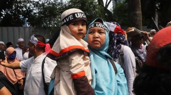 Ibu dan anak mengikuti aksi bela Uighur di depan Kedutaan Besar Republik Rakyat China, Kuningan, Jakarta Selatan, Jumat (27/12). [Suara.com/Alfian Winanto]