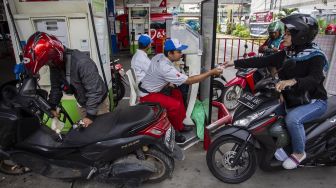 Pengendara motor melakukan transaksi saat antre untuk mengisi bahan bakar di SPBU Pertamina di kawasan Kuningan, Jakarta, Selasa (31/12). [ANTARA FOTO/Dhemas Reviyanto]