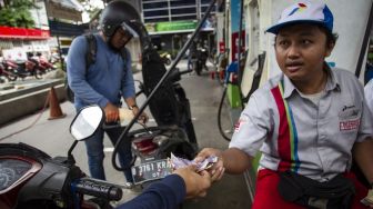 Pengendara motor melakukan transaksi saat antre untuk mengisi bahan bakar di SPBU Pertamina di kawasan Kuningan, Jakarta, Selasa (31/12). [ANTARA FOTO/Dhemas Reviyanto]