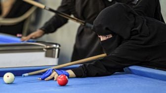 Seorang wanita bercadar membidik bola selama kejuaraan biliar lokal di sebuah gedung olahraga di ibu kota Sanaa, Yaman, Senin (16/12). [Mohammed HUWAIS / AFP]