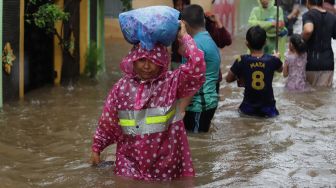 Sejumlah warga melintasi jalan yang terendam banjir di kawasan Jatipadang, Pasar Minggu, Jakarta Selatan, Rabu (1/1). [Suara.com/Angga Budhiyanto]