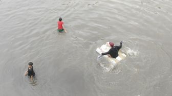 Sejumlah bocah bermain saat banjir yang merendam Jalan Letjen S Parman dan tol dalam kota di Jakarta Barat, Rabu (1/1). [ANTARA FOTO/Nova Wahyudi]
