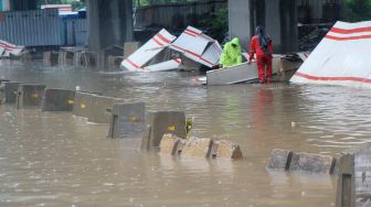 Petugas membetulkan pembatas jalan yang diterjang banjir di jalan HR Rasuna Said, Jakarta Selatan, Rabu (1/1). [Suara.com/Oke Atmja]