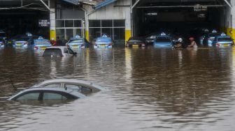 Warga mengevakuasi mobil taksi di pool taksi Kramat Jati, Jalan Raya Pondok Gede, Jakarta, Rabu (1/1).  [ANTARA FOTO/Galih Pradipta]