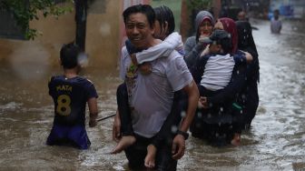 Sejumlah warga melintasi jalan yang terendam banjir di kawasan Jatipadang, Pasar Minggu, Jakarta Selatan, Rabu (1/1). [Suara.com/Angga Budhiyanto]