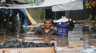 Seorang warga menggotong barang saat banjir merendam kawasan Kebon Pala, Jakarta Timur, Rabu (1/1). [Suara.com/Angga Budhiyanto]