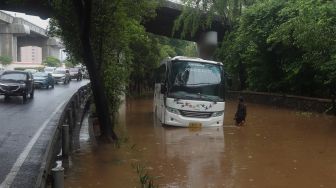Sebuah bus terjebak banjir di kawasan Kebon Pala, Jakarta Timur, Rabu (1/1). [Suara.com/Angga Budhiyanto]
