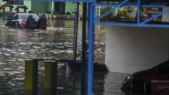 Warga mengevakuasi mobil di pool taksi Kramat Jati, Jalan Raya Pondok Gede, Jakarta, Rabu (1/1). [ANTARA FOTO/Galih Pradipta]