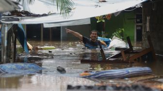 Seorang warga menggotong barang saat banjir merendam kawasan Kebon Pala, Jakarta Timur, Rabu (1/1). [Suara.com/Angga Budhiyanto]