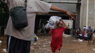 

Pedagang menyelamatkan barang dagangannya dari banjir yang merendam Pasar Cipulir, Jakarta Selatan, Rabu (1/1). [Suara.com/Angga Budhiyanto]

