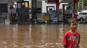 Warga melintas di depan SPBU Shell yang terbakar di Jalan Daan Mogot, Jakarta Barat, Kamis (2/1). [Suara.com/Angga Budhiyanto]  