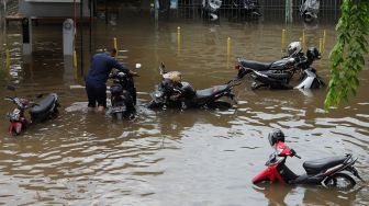 Petugas menata sepeda motor yang terendam banjir di Jalan Daan Mogot, Jakarta Barat, Kamis (2/1). [Suara.com/Angga Budhiyanto]  
