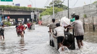 Ojek gerobak mendorong penumpang diatasnya untuk menyeberang Persimpangan Puri Kembangan, Kembangan Pasar Minggu, Jakarta Barat, Jumat (3/1).  [Suara.com/Alfian Winanto]