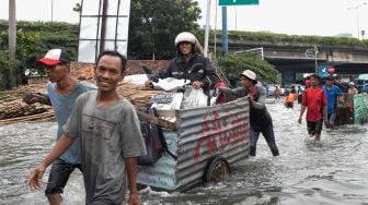 Ojek gerobak mendorong penumpang diatasnya untuk menyeberang Persimpangan Puri Kembangan, Kembangan Pasar Minggu, Jakarta Barat, Jumat (3/1).  [Suara.com/Alfian Winanto]