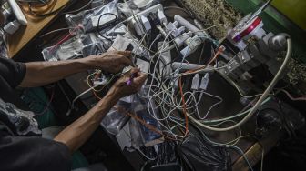 Warga melakukan pengisian daya untuk telepon genggamnya saat banjir melanda di kawasan Kembangan, Jakarta Barat, Kamis (2/1). [ANTARA FOTO/Muhammad Adimaja]