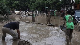 Warga membersihkan endapan lumpur di Perumahan Pondok Mitra Lestari, Bekasi, Jawa Barat, Jumat (3/1). [Suara.com/Angga Budhiyanto]