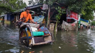 Pengayuh becak malang melintang menerobos banjir untuk mencari penumpang di Kawasan Teluk Gong, Penjaringan, Jakarta Utara, Sabtu (4/1). [Suara.com/Alfian Winanto]