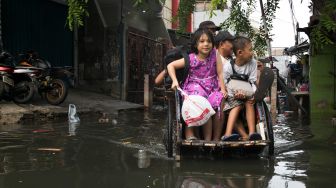 Pengayuh becak membawa penumpang menerobos banjir di Kawasan Teluk Gong, Penjaringan, Jakarta Utara, Sabtu (4/1). [Suara.com/Alfian Winanto]