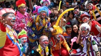 Foto bersama para badut komunitas Aku Badut Indonesia (ABI) bersama dengan anak-anak korban banjir di posko pengungian bencana banjir Gor  Pengadegan, Jakarta Selatan, Selasa (07/01). (suara.com/Alfian Winanto)