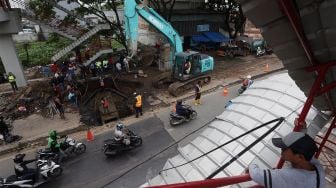 Warga menyaksikan proses perbaikan jalan yang amblas di Jalan Daan Mogot, Kota Tangerang, Banten, Senin (13/1). [Suara.com/Angga Budhiyanto]