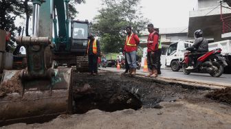 Petugas melakukan proses perbaikan jalan yang amblas di Jalan Daan Mogot, Kota Tangerang, Banten, Senin (13/1). [Suara.com/Angga Budhiyanto]