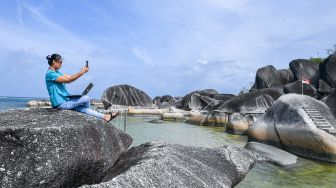 Seorang pengunjung berswafoto di atas bongkahan batu granit di Alif Stone Park, Desa Sepempang, Kabupaten Natuna, Provinsi Kepulauan Riau, Senin (13/1). [ANTARA FOTO/M Risyal Hidayat]