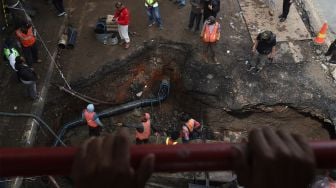 Petugas melakukan proses perbaikan jalan yang amblas di Jalan Daan Mogot, Kota Tangerang, Banten, Senin (13/1). [Suara.com/Angga Budhiyanto]