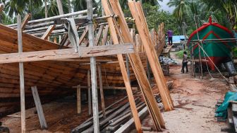 Pekerja menyelesaikan pembuatan kapal motor di Desa Tanjung, Natuna, Kepulauan Riau, Selasa (14/1). [ANTARA FOTO/M Risyal Hidayat]