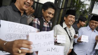 Sejumlah pegiat antikorupsi yang tergabung dalam koalisi masyarakat sipil menggelar aksi sebelum menyerahkan jamu antidiare di gedung KPK, Jakarta, Rabu (15/1). [ANTARA FOTO/Hafidz Mubarak] 
