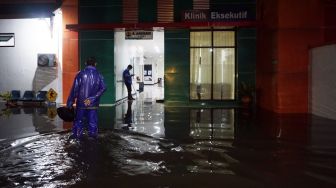 Warga berjalan di sekitar Rumah Sakit Umum Daerah (RSUD) Kraton yang tergenang banjir di Pekalongan, Jawa Tengah, Senin (20/1) malam.  [ANTARA FOTO/Harviyan Perdana Putra]