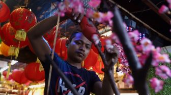 Pekerja menyelesaikan pesanan pohon bunga Meihua di toko di kawasan pasar Asemka, Jalan Pintu Kecil, Jakarta Barat, Selasa (21/1). [Suara.com/Angga Budhiyanto]