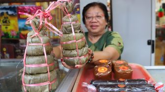 Pedagang menunjukan kue keranjang bungkus daun pisang, yang merupakan kue khas Imlek yang dijual di berbagai toko di sepanjang jalan Surya Kencana, Bogor, Selasa (21/02). [Suara.com/Alfian Winanto]